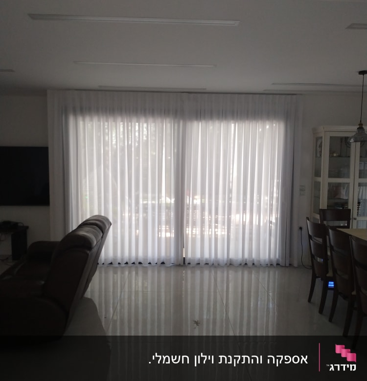 וילון לבן גדול תלוי על חלון זכוכית רחב